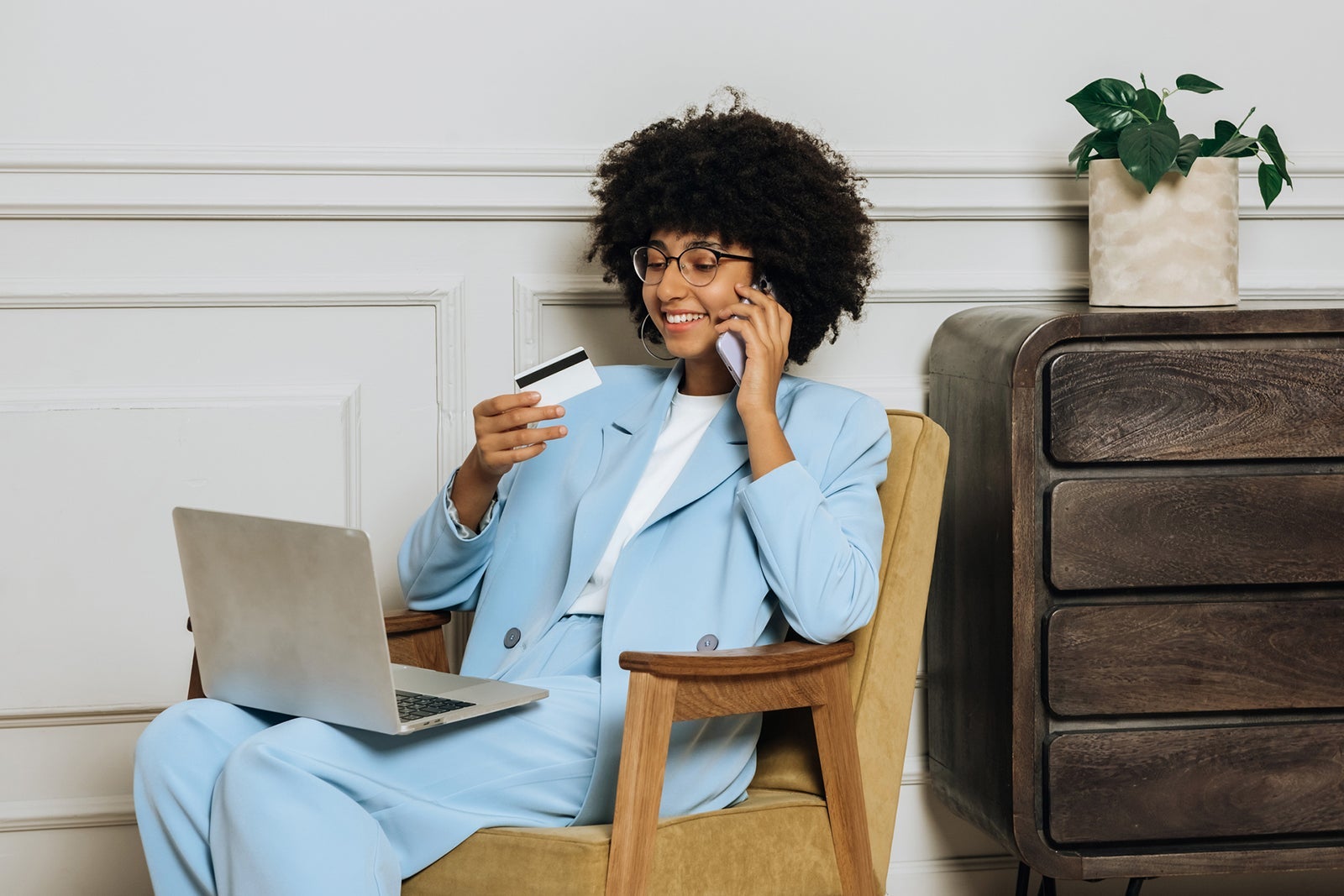 African woman with phone and credit card pays via laptop with internet. Business and credit concept