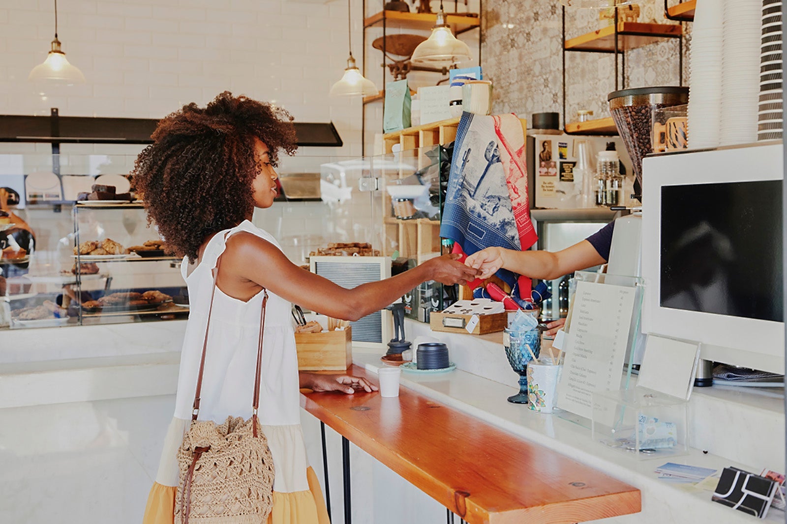 Medium wide shot of woman using credit card to pay in coffee shop