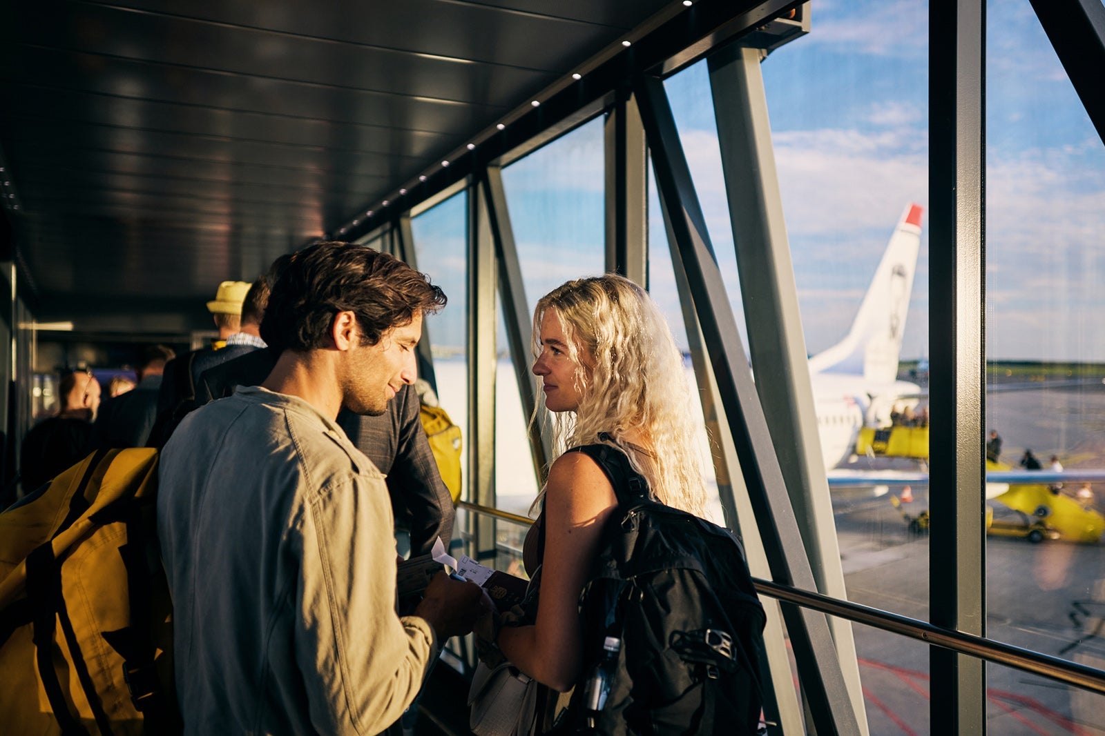 Young adult couple embarking on a weekend vacation, boarding the plane on the runway.