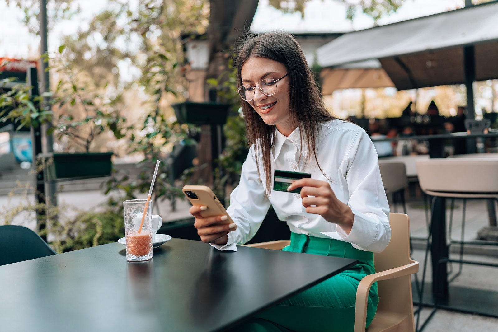Young woman sitting at a cafe and shopping on her phone
