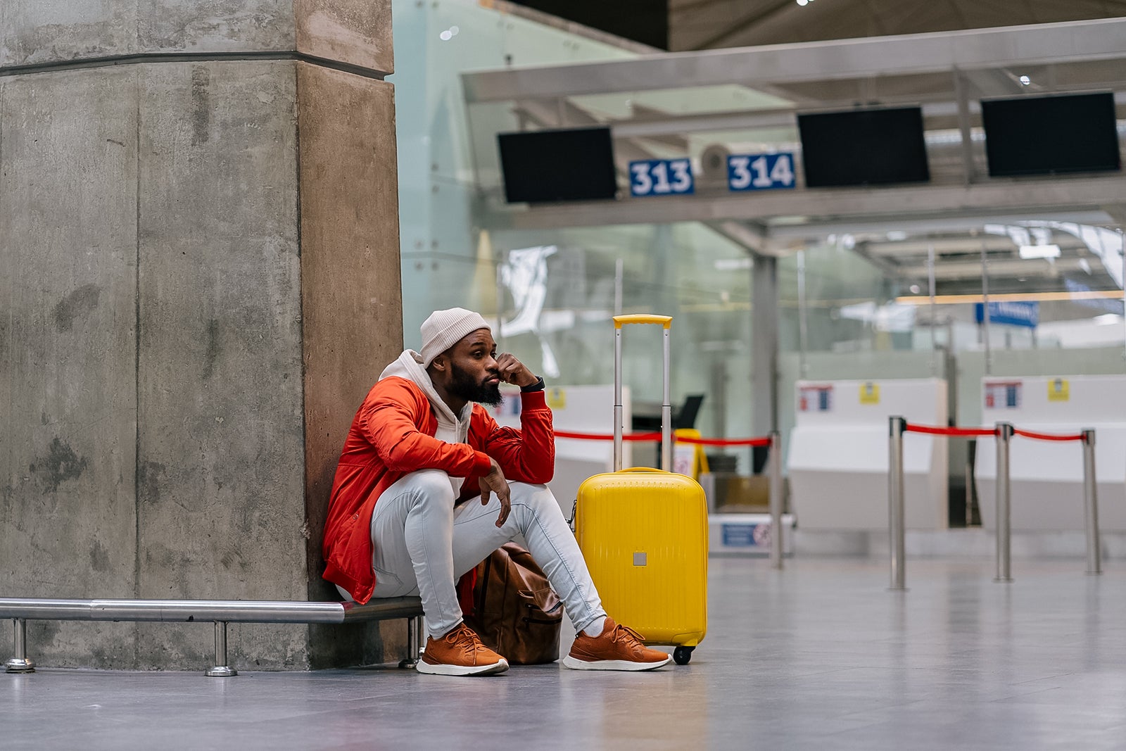 Exhausted man on a long night connection at airport, waiting for a plane sitting in terminal