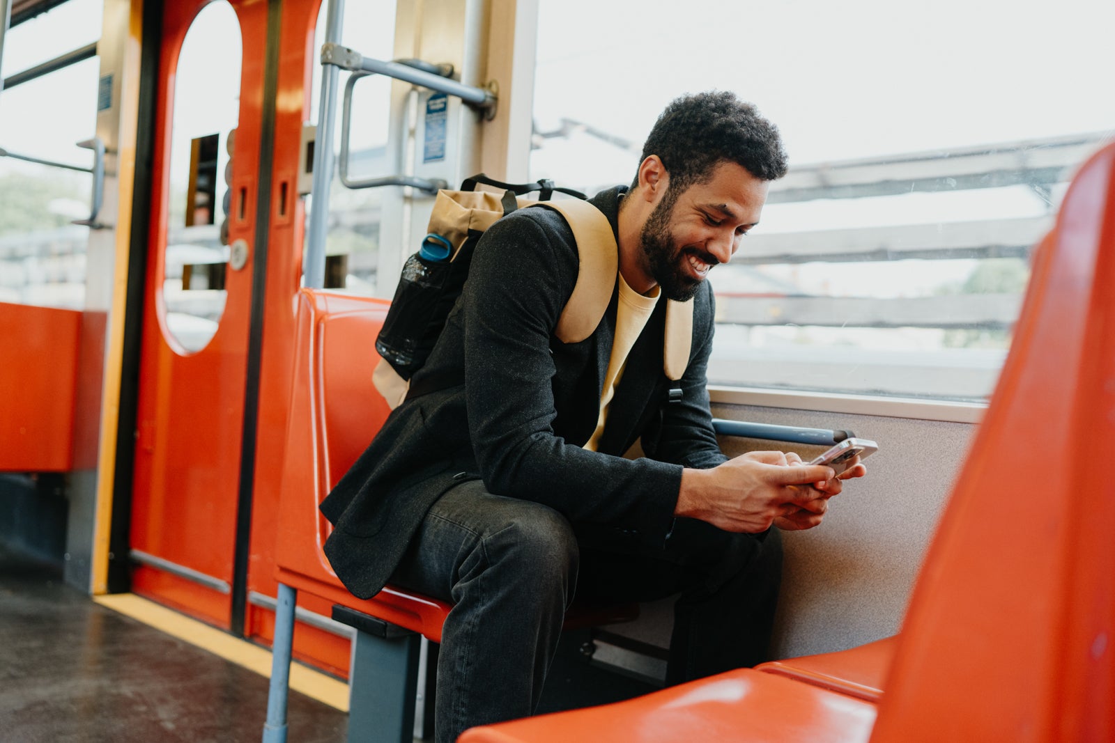 Handsome man traveling by city train, scrolling on a smartphone. Man heading home after a long day at work. The single man commutes alone.