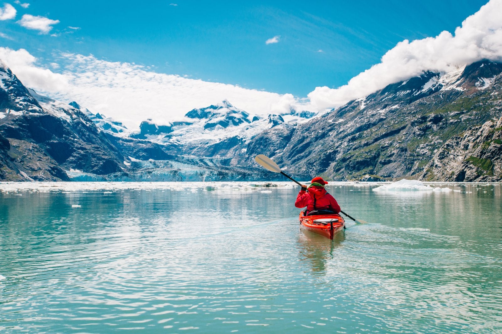 Woman kayaking in Glacier Bay National Park with glacier in background